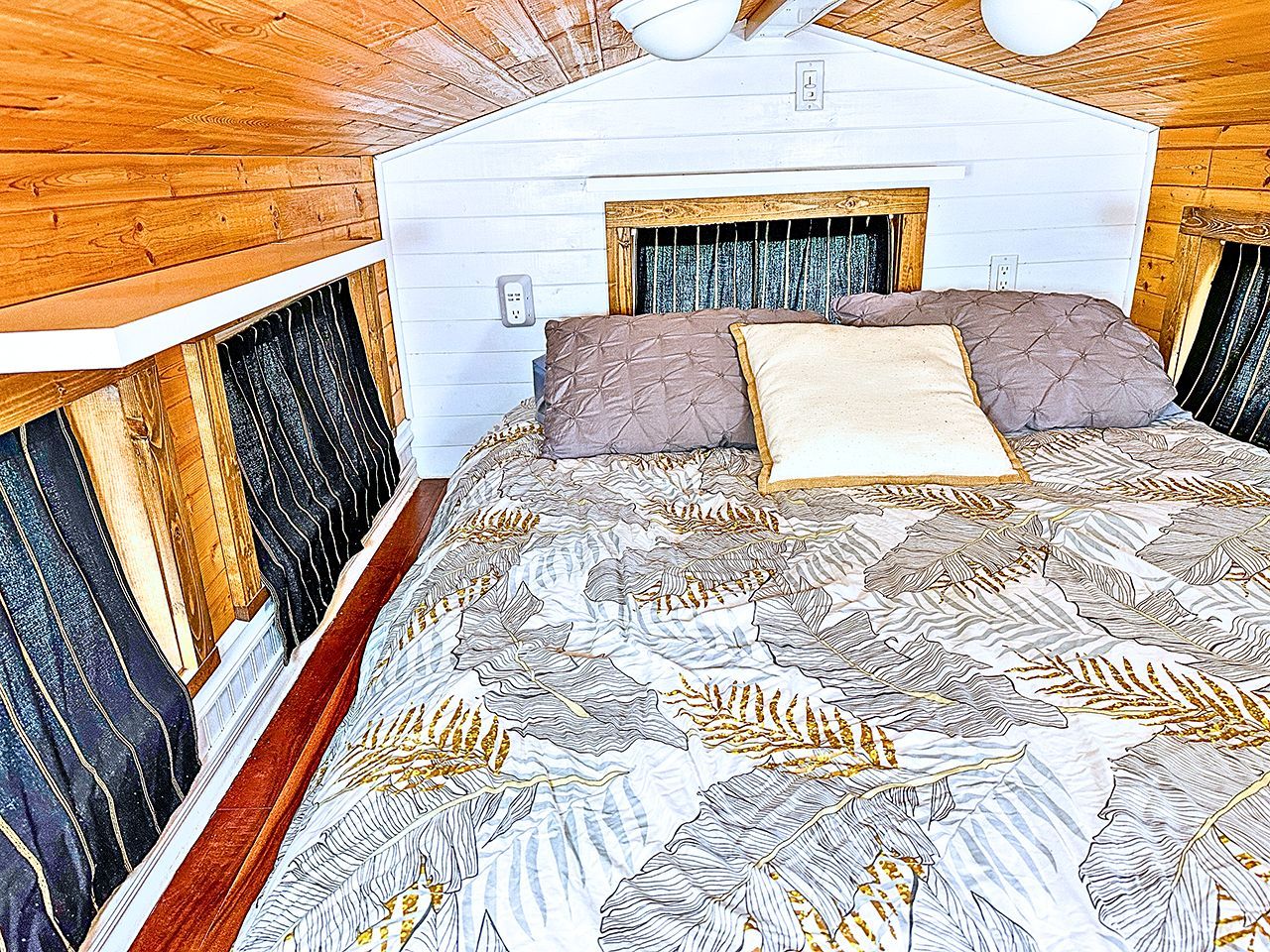 Un dormitorio con una cama, paredes de madera y una ventana.