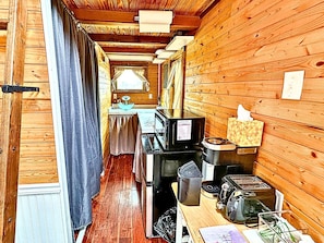 A compact kitchen with wooden walls, a microwave, a toaster, and a sink.