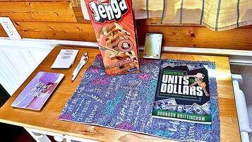 Una mesa de madera con una caja de Jenga, un cuaderno, un bolígrafo y un libro titulado 'Converting Units to Dollars'.