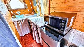 Cocina compacta equipada con microondas, horno y una pequeña mesa con lavamanos.
