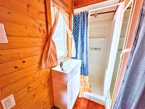 Un baño con paredes de madera, un lavamanos y una ducha.