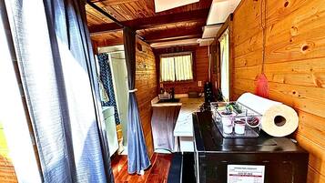 A narrow hallway with wooden walls, a kitchen area with a sink and countertop, and a window with curtains.