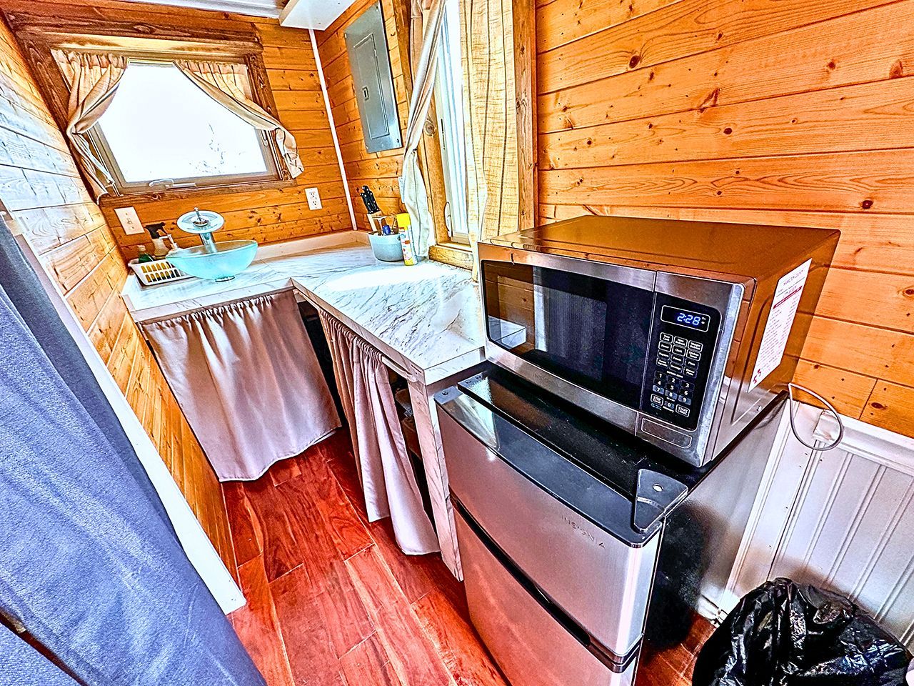 A compact kitchen with a microwave, oven, and a small table with a sink.