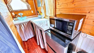 A compact kitchen with a microwave, oven, and a small table with a sink.
