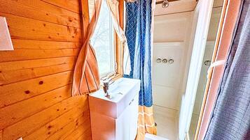 A bathroom with wooden walls, a sink, and a shower.