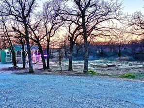 A gravel area with trees and a small building.