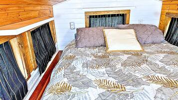 Un dormitorio con una cama, paredes de madera y una ventana.