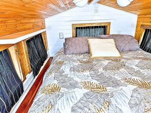 A bedroom with a bed, wooden walls, and a window.