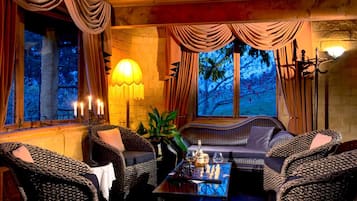 A cozy room with wicker furniture, a table with a chess set, and a wall-mounted lamp.