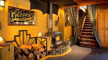 Ein gemütliches Interieur mit Kaminofen, einer Treppe und einem Schild für 'Glonops EATERIE'.