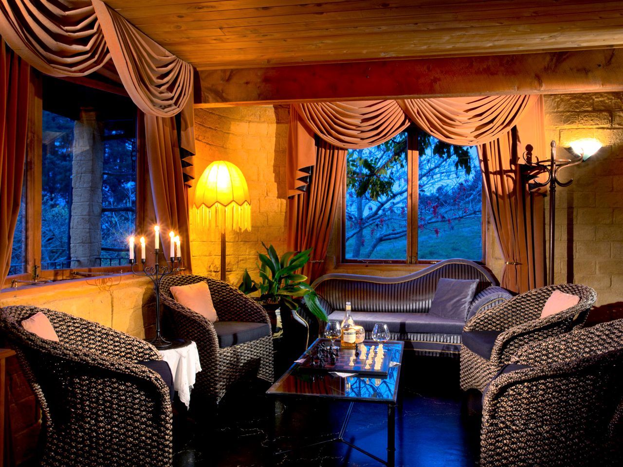 A cozy room with wicker furniture, a table with a chess set, and a wall-mounted lamp.