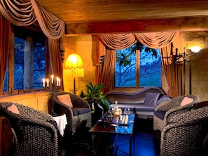 A cozy room with wicker furniture, a table with a chess set, and a wall-mounted lamp.