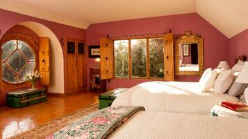 A bedroom with a large bed, a window with wooden shutters, and a mirror with a decorative frame.