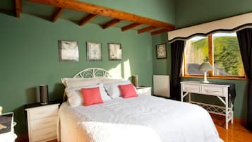 Une chambre à coucher avec un lit, des tables de chevet, un bureau et une fenêtre avec des rideaux.