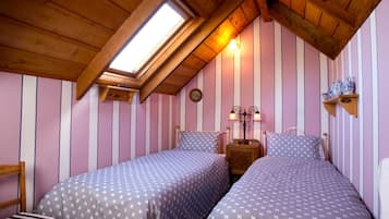 A bedroom with two beds, a skylight, and a wooden ceiling.