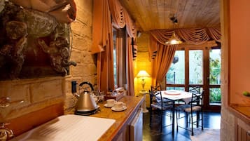 A rustic kitchen with a stone wall, wooden cabinets, and a dining area with a table and chairs.