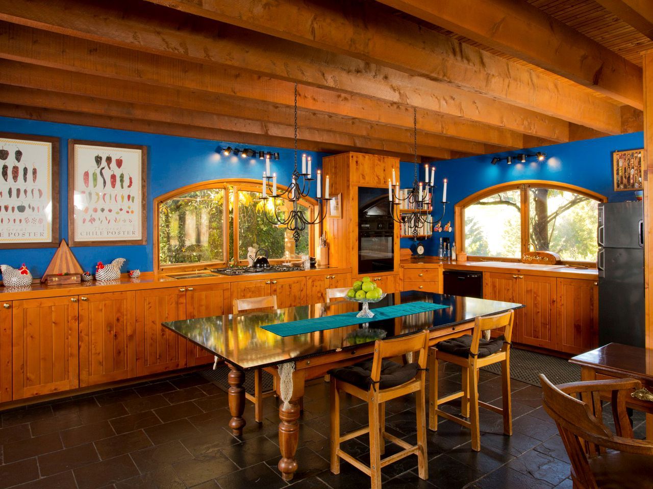 Une cuisine en bois avec une table à manger au plateau en verre, des placards en bois et une fenêtre donnant sur un espace verdoyant.