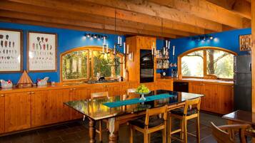 Une cuisine en bois avec une table à manger au plateau en verre, des placards en bois et une fenêtre donnant sur un espace verdoyant.
