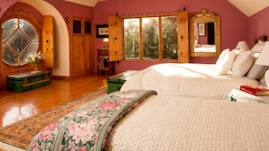 A bedroom with a large bed, a window with wooden shutters, and a mirror with a decorative frame. - Luxury Castle for Large Groups in Nelson, New Zealand (Upper Moutere)