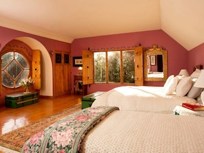 A bedroom with a large bed, a window with wooden shutters, and a mirror with a decorative frame. - Luxury Castle for Large Groups in Nelson, New Zealand (Upper Moutere)