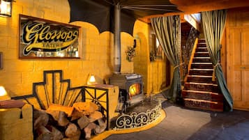 A cozy interior with a wood-burning stove, a staircase, and a sign for 'Glonops EATERIE'.
