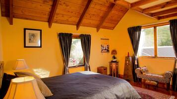 A bedroom with a bed, a nightstand, a lamp, a dresser, a chair, and a window with curtains.