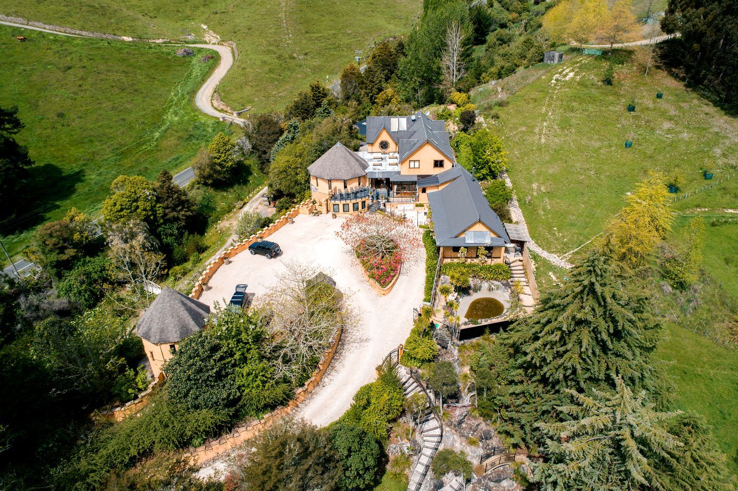 A large house with a spacious driveway, surrounded by lush greenery and trees.