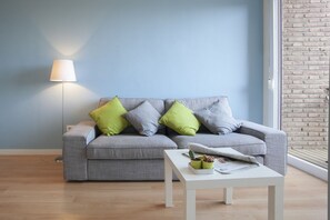 En stue med en grå sofa, et hvidt sofabord og en lampe.