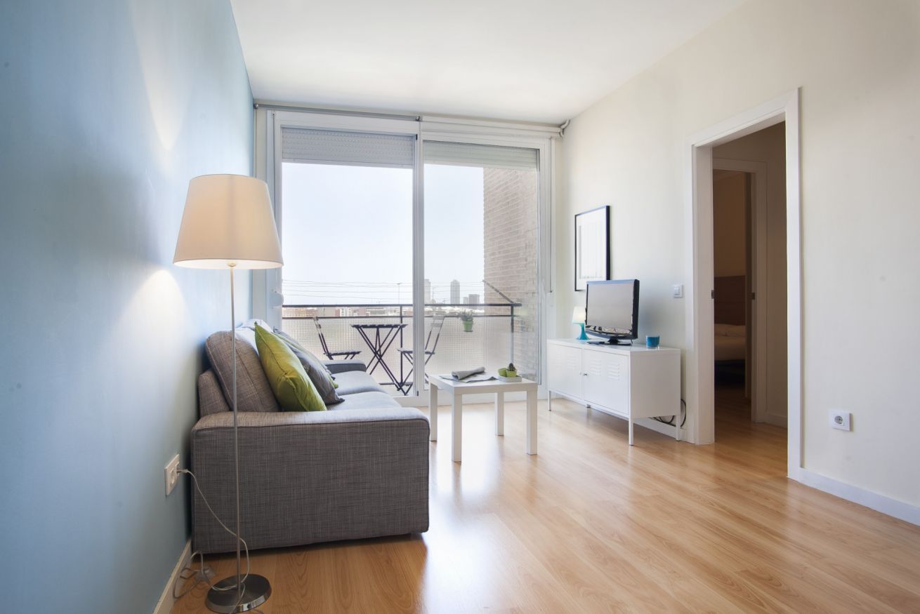 Ein modernes Wohnzimmer mit einer Couch, einem Fernseher und einem Balkon mit Blick.