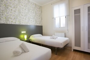 A hotel room with two beds, a window, a wardrobe, and a wall with a pattern. - Apartment with Balcony near Sagrada Familia – Aragón 528Perfect for families, getaways with friends, or romantic weekends, this cozy three-bedroom, two-bathroom apartment offers everything you need to enjoy Barcelona like a true local. Just steps from (Barcelona)