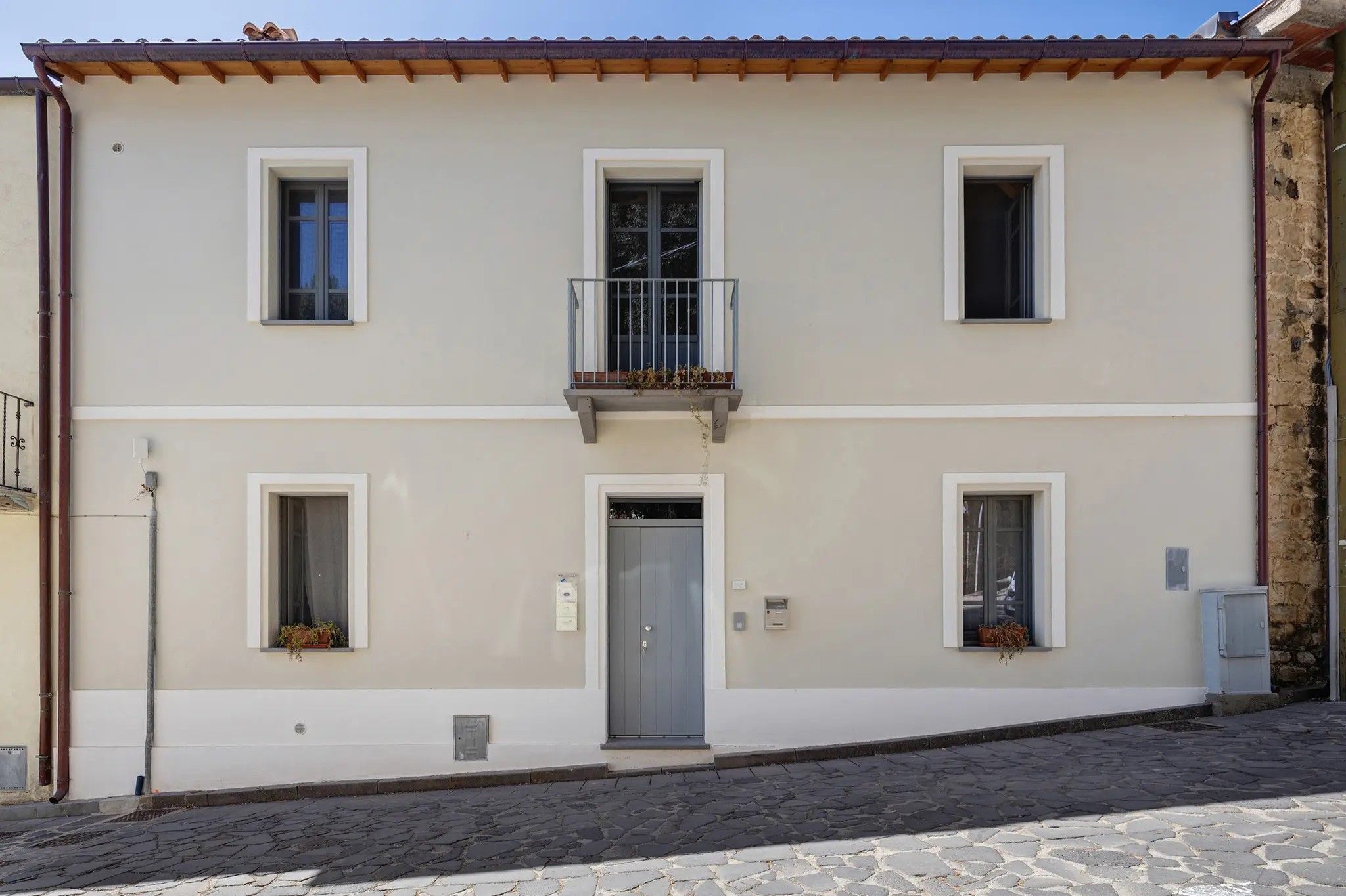 Un edificio a due piani con un balcone, una porta e finestre.