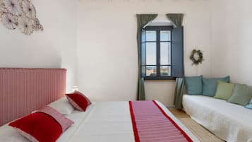 Una camera da letto con un letto, un divano, una finestra con tende e un elemento decorativo a parete.
