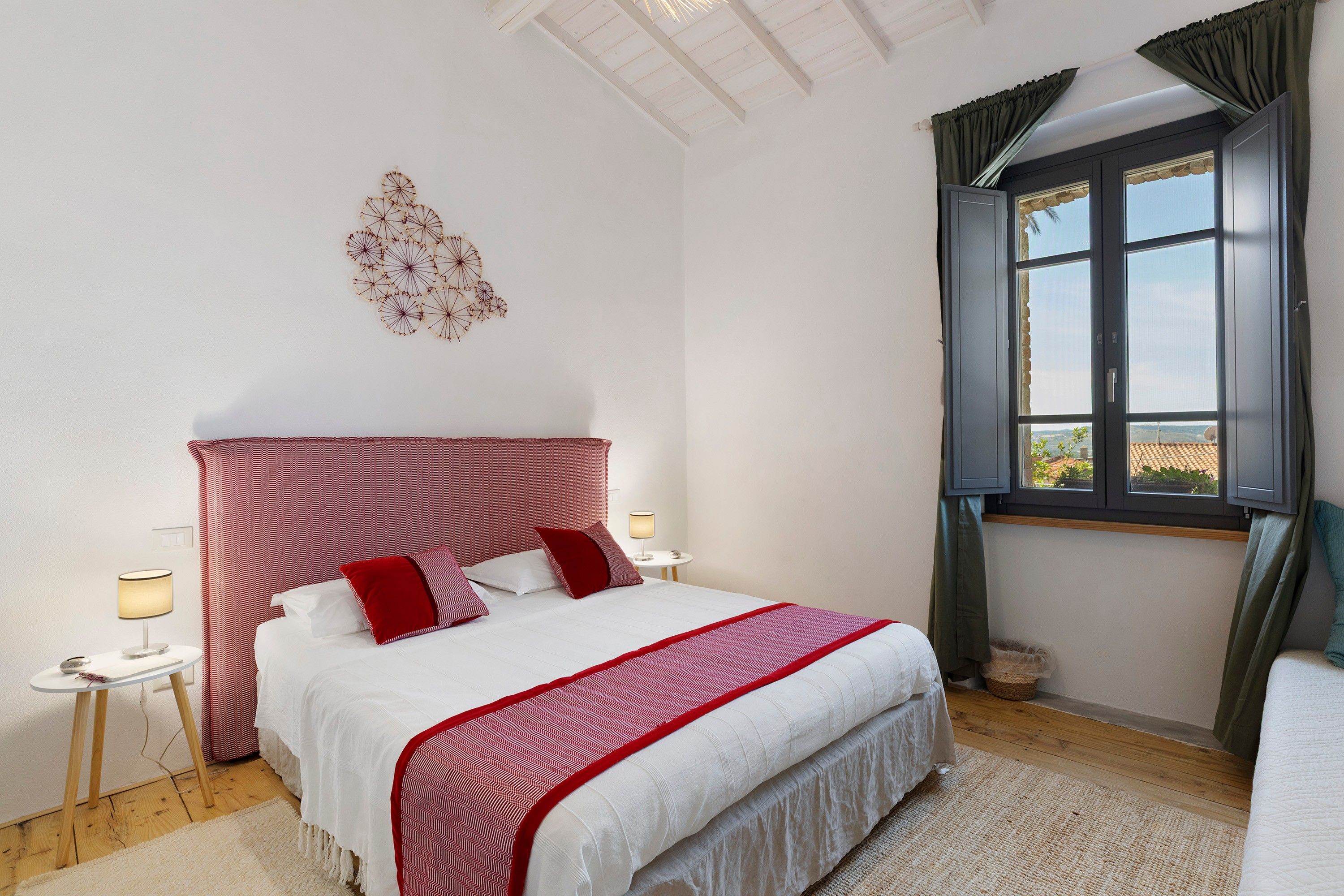 Ein Schlafzimmer mit Bett, Nachttischen, einem Fenster mit Vorhängen und einer Wanddekoration.