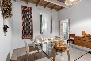 A dining area with a glass table, white chairs, and a wooden cabinet.