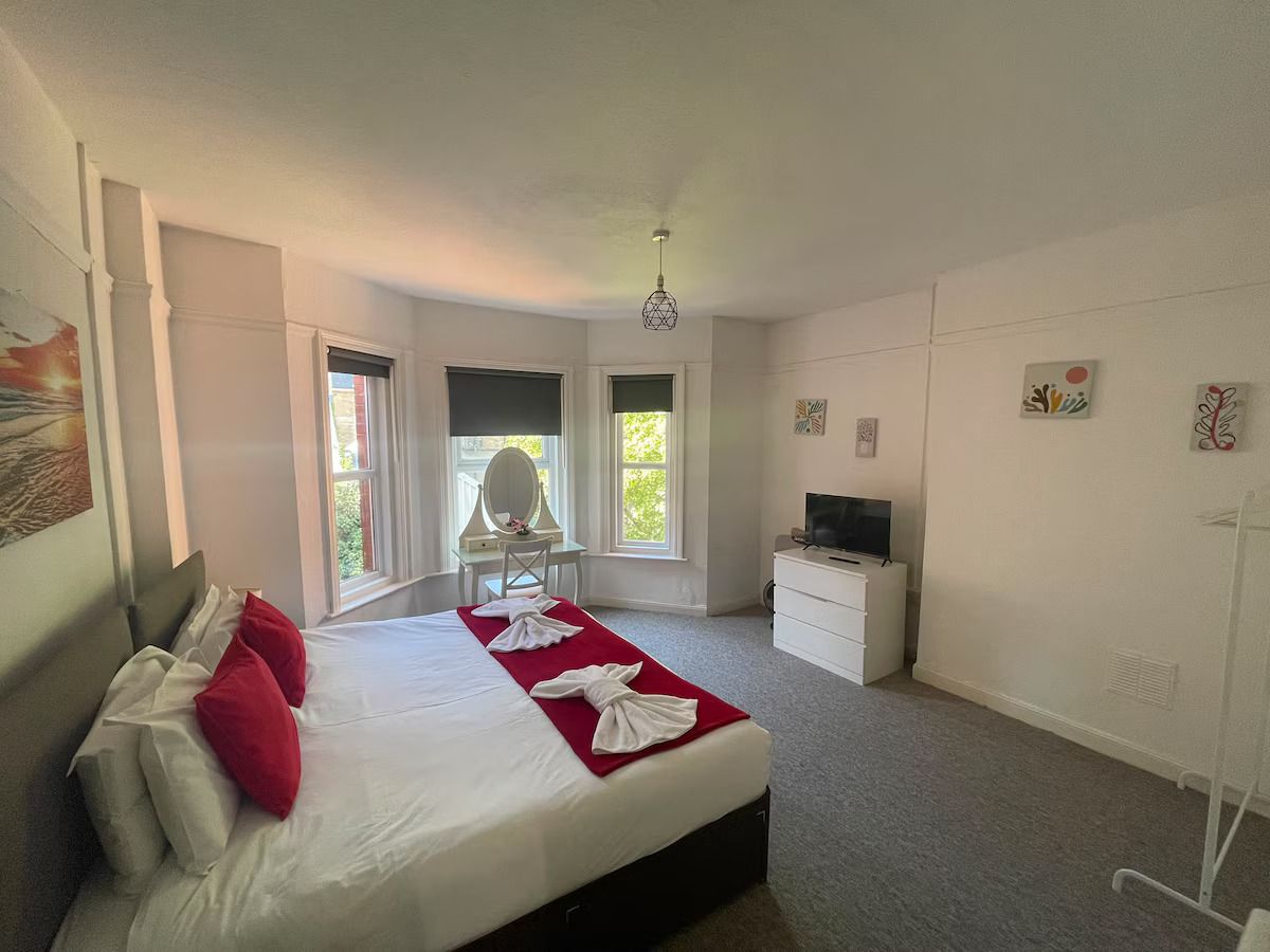 Quarto de hotel com cama, escrivaninha, televisão e obras de arte nas paredes.