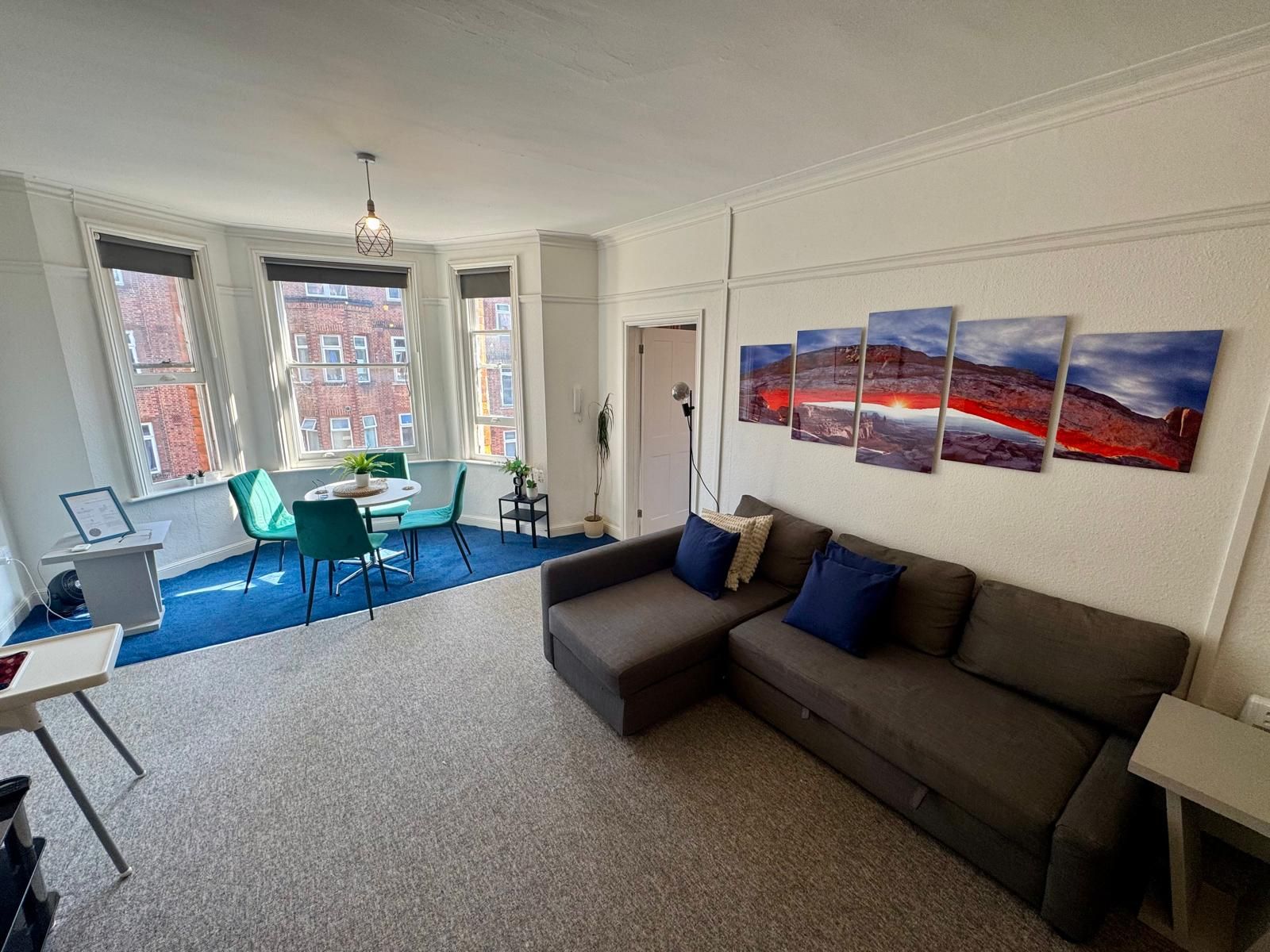 Een moderne woonkamer met een hoekbank, een eethoek met tafel en stoelen, en grote ramen met uitzicht over de stad.