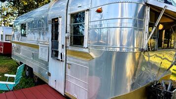 A vintage trailer with a small porch and a window.