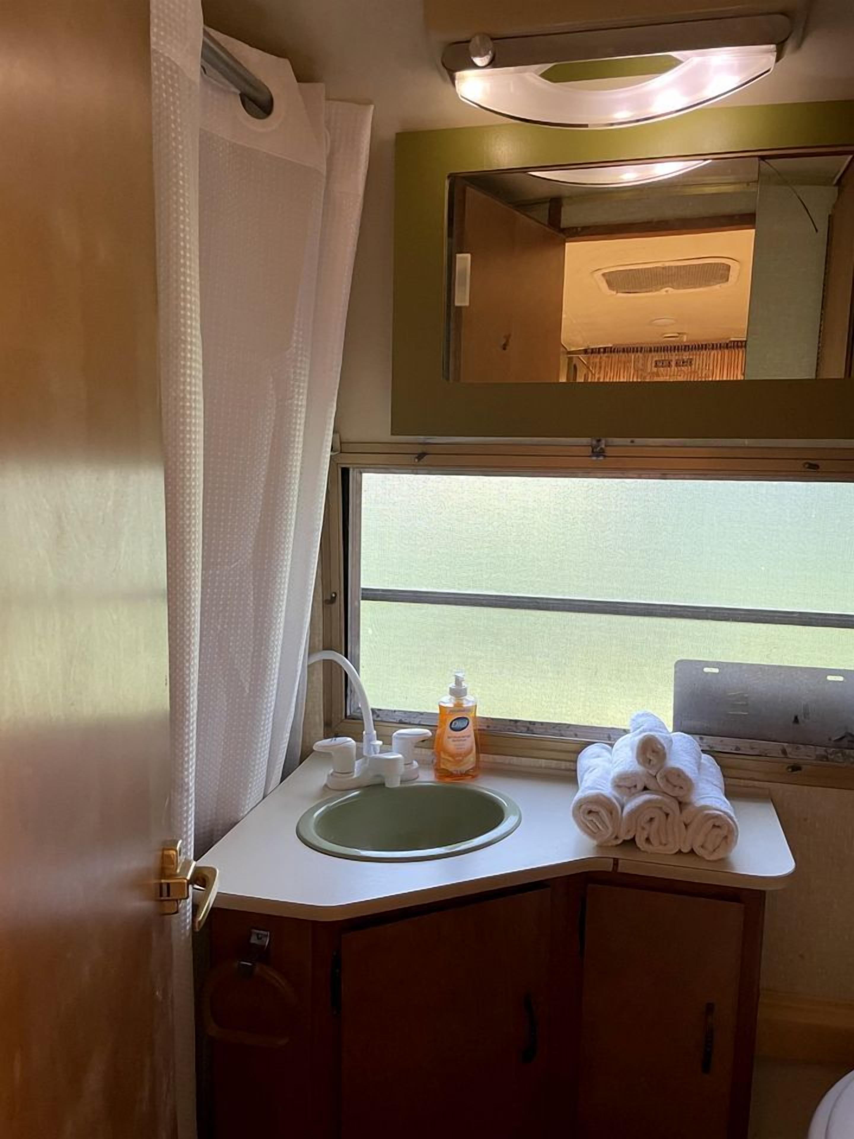Un bagno con lavandino, specchio e finestra.