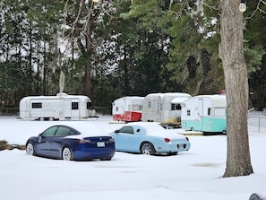 Un parking où les voitures et les remorques sont recouvertes de neige.