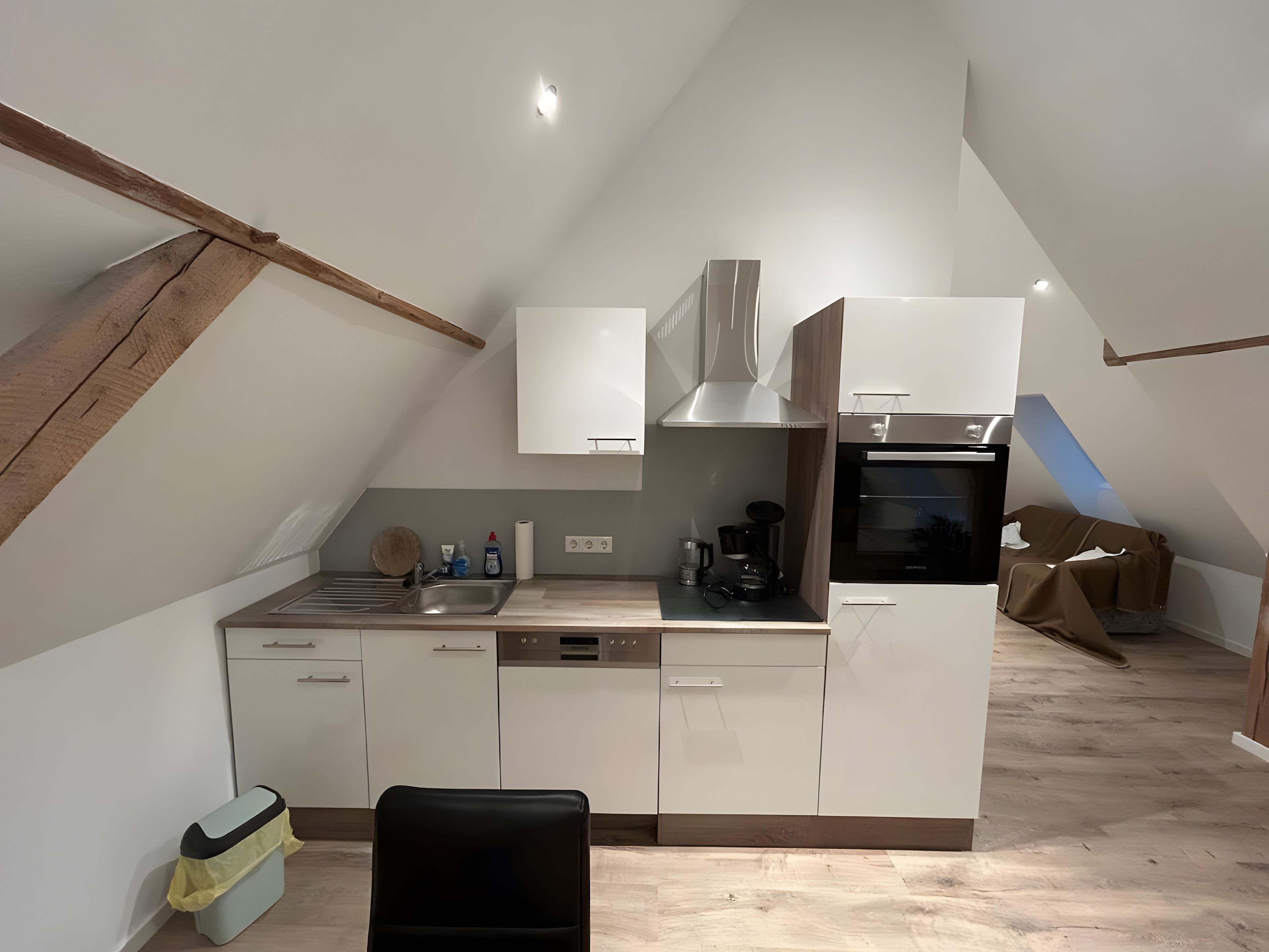 A modern kitchen with white cabinets, a stainless steel sink, and a built-in oven.