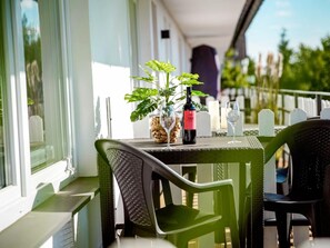 A balcony with a table set for two, featuring a bottle of wine, a glass, and a potted plant. - Holiday Apartment 712 (Winterberg)