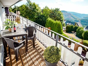 A balcony with a table, chairs, and a potted plant. - Holiday Apartment 712 (Winterberg)