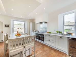 A modern kitchen with white cabinetry, a central island, and a dining area with a wooden table and chairs.