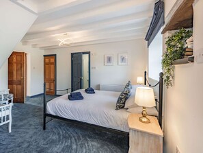 A bedroom with a bed, bedside table, lamp, and a view of the outside.
