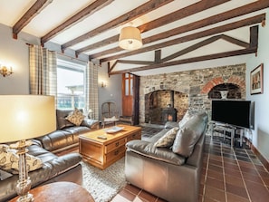 A cozy living room with leather sofas, a wooden coffee table, and a stone fireplace.