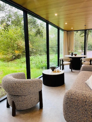 A modern interior with large windows, a round table, and two sofas. - S.P.A. Parel in 't Groen (Moergestel)