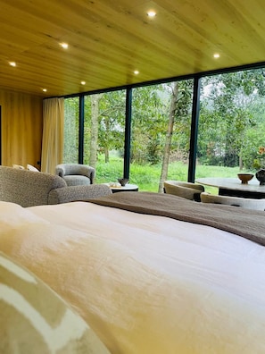 Un dormitorio con una cama grande, un sofá y una silla, con vista a zonas verdes.