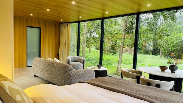 Une chambre moderne avec un grand lit, un canapé, un fauteuil et une table sur laquelle est posé un vase.