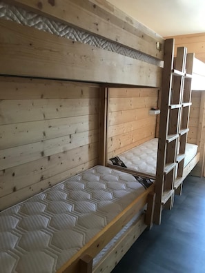 Uma cama beliche com colchão e cabeceira de madeira.
