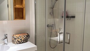 A modern bathroom with a glass-enclosed shower, a vanity with a mirror, and a wooden cabinet. - Apartment in Les Arcs 1800 for 8 people (Bourg-Saint-Maurice)